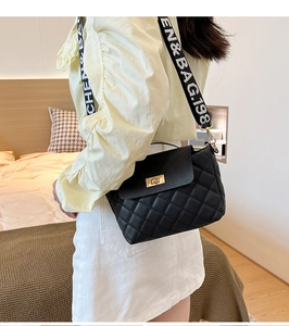 Close-up of black quilted bucket bag featuring a gold metal lock and wide branded strap