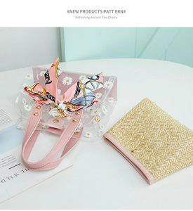 Detail of daisy print PVC tote with pink handles and straw inner pouch on table