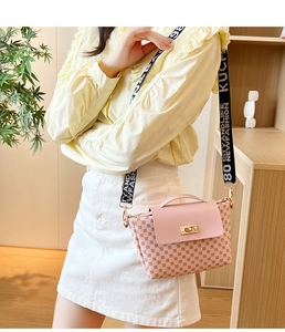 Detail of light pink bucket bag with gold metal lock and wide jacquard logo shoulder strap