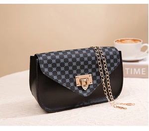 Detail of elegant black leather mini bag with blue textured flap and gold push-lock