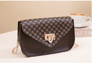Detail of a dark brown mini crossbody bag with gold clover pattern and metal chain