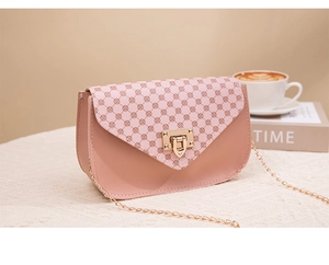 Detail of pink mini bag featuring geometric print, gold metal clasp and chain strap