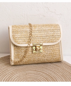 Detail of woven straw handbag with golden twist lock and elegant metal chain strap