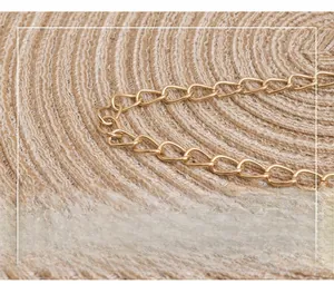 Detail of premium gold metal chain strap on textured woven brown leather small square bag