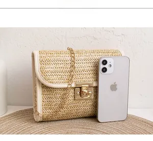 Detailed view of woven straw crossbody bag with golden chain and lock on straw mat