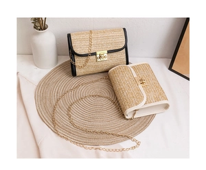 Detail of straw woven chain crossbody bags with metal clasp on a rustic setting