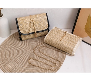 Detail of woven straw flap bags with gold chain straps and elegant metal tassels