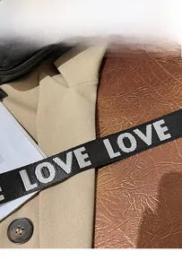 Detail of a wide woven black shoulder strap with white LOVE embroidery for handbags
