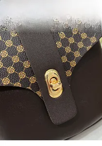 Detail view of vintage brown bag featuring clover print and gold metal latch closure