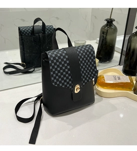 Detail of mini black crossbody bag with dot patterns and golden twist lock on marble surface