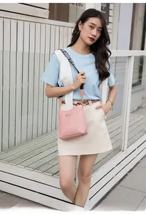 Detail of pink crocodile pattern crossbody bag with a stylish wide woven shoulder strap