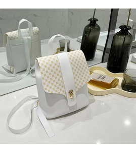 Detail of mini white backpack with yellow polka dots and golden metal twist lock closure
