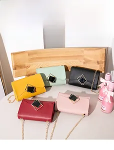 Detail shot of five colorful chain crossbody bags with square metal buckles on a chair