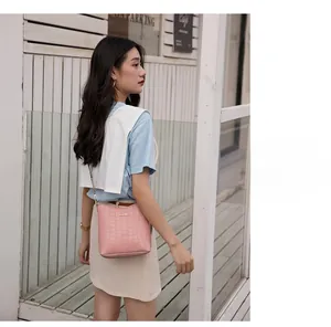 Pink crocodile pattern bucket bag with golden buckle and wide strap on model