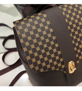 Close-up of brown crossbody bag with gold clover print and metallic twist lock detail