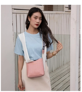 Close-up of pink crocodile texture crossbody bag with G.1980 logo printed woven strap