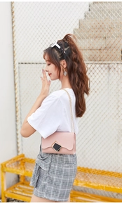 Detail shot of a light pink crossbody bag with double square metal buckle and gold chain