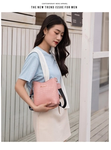 Pink croc-embossed bucket bag detail with stylish branded wide textile shoulder strap