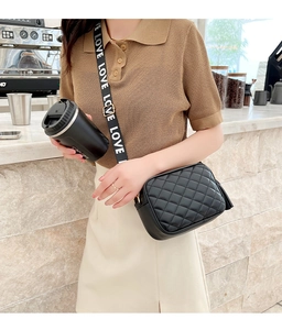 Detail of black quilted crossbody bag featuring a wide LOVE logo strap and leather tassel