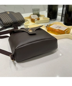 Detail of vintage brown leather phone bag showing grid texture and gold twist lock