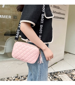 Detailed shot of pink quilted crossbody bag with wide LOVE lettered strap and tassel
