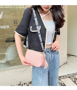 Detail of pink quilted crossbody bag with embroidered pattern and LOVE lettered strap