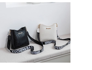 Close-up of crocodile texture bucket bags with white letter printed nylon straps