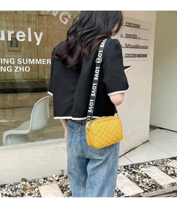 Detail of yellow quilted camera bag with stylish black and white LOVE letter strap