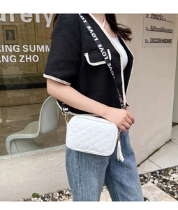 Detail of white quilted crossbody bag with fringe tassel and LOVE letter strap