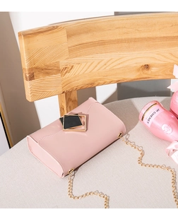 Close-up of pink leather crossbody bag featuring gold chain and geometric square buckle
