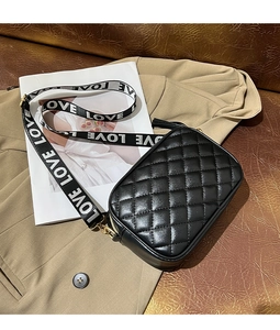 Detail of black quilted crossbody bag with stylish LOVE letter patterned wide strap