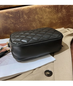 Close-up of black quilted leather crossbody bag with gold hardware and tassel detail