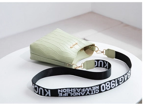 Macro detail of mint green crocodile embossed texture with printed fabric shoulder strap