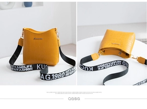 Close-up of yellow crocodile texture bucket bag with a stylish wide printed shoulder strap