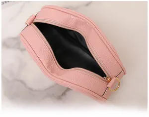 Détail du petit sac rond rose avec texture grainée litchi et fermeture éclair dorée