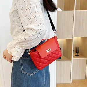 Quilted red bucket bag for women with wide lettered strap shown in a lifestyle shot