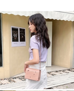 Détail du sac bandoulière rose avec motifs ajourés et lettrage fashion élégant