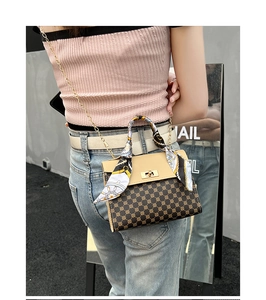 Detail of crossbody bag with monogram pattern, silk scarf handle and gold chain strap