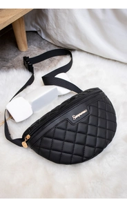 Detail der schwarzen gesteppten Bauchtasche mit goldenem Logo und breitem Gurt