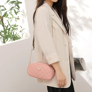 Pink quilted bow crossbody bag with gold chain strap shown on a white blazer model