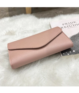 Pink litchi texture envelope clutch bag shown on a white plush rug with a classic book