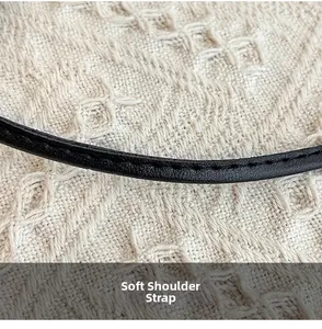 Détail de la bandoulière en cuir noir souple avec couture fine sur texture tissée