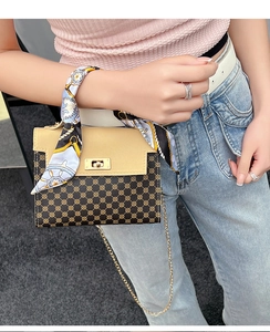 Detail of a dual-tone handbag featuring geometric patterns, silk scarf and gold chain strap