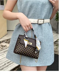 Detail of a brown monogram handbag with scarf handle and gold chain strap