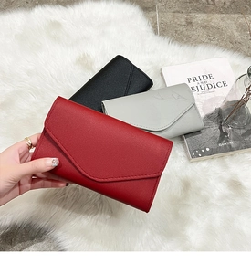 Close-up of three textured envelope wallets on a plush rug with decorative props