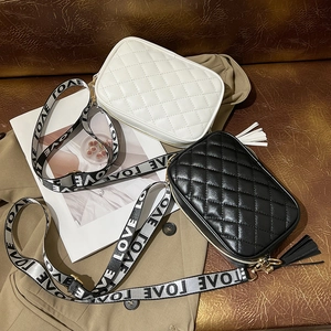 Quilted crossbody bag with LOVE strap and tassel, shown in black and white leather styles
