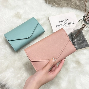 Detail of envelope-style long leather wallets in pastel blue and pink on plush fabric