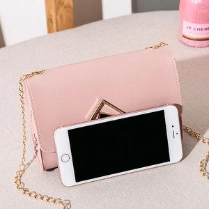 Pink mini crossbody bag with gold chain strap and square buckle shown with phone for size