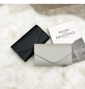 Litchi texture envelope clutches in black and light sage green on plush white faux fur