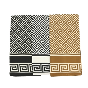Close-up of geometric Greek key pattern on folded silk scarves in three colors